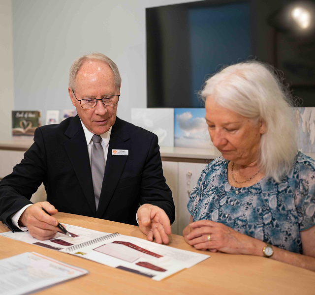 funeral director with client looking at a booklet for funerals