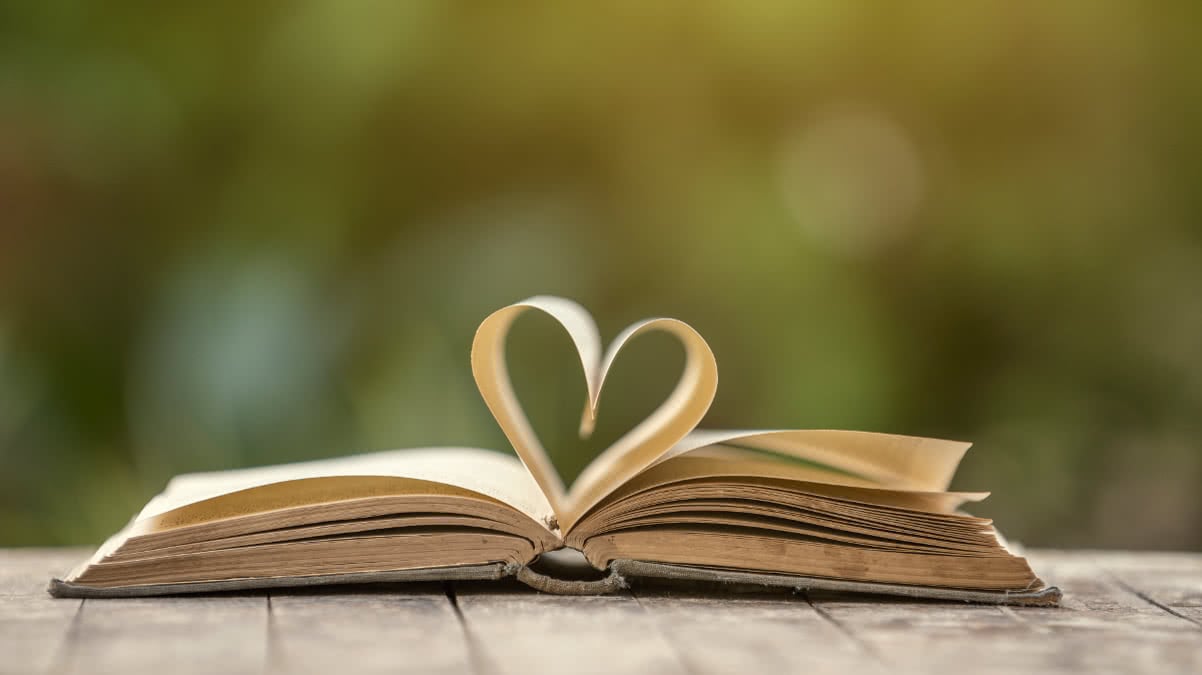 An image of an open book which has the middle pages arranged in a shape of a heart