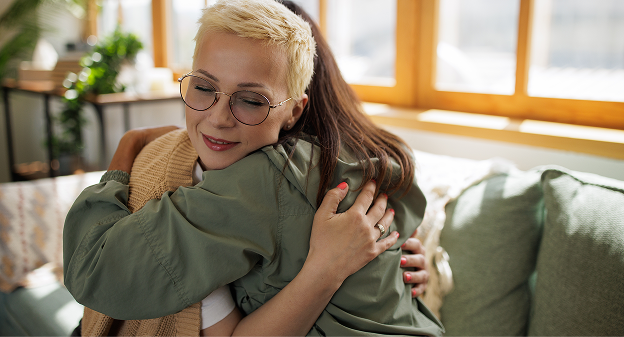 woman with glasses hugging friend on lounge